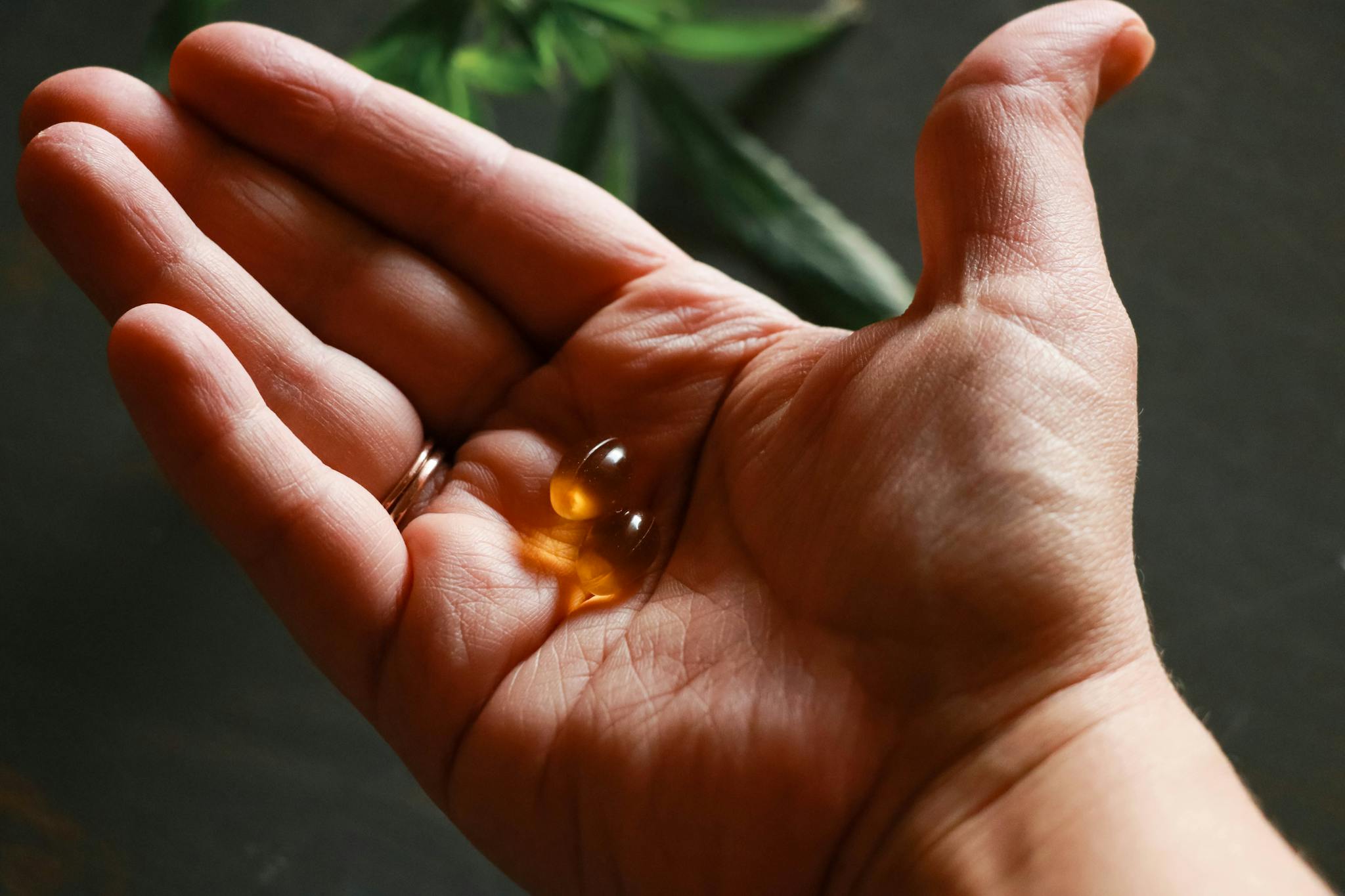 Close-up of a hand holding soft gel capsules, highlighting health and wellness.