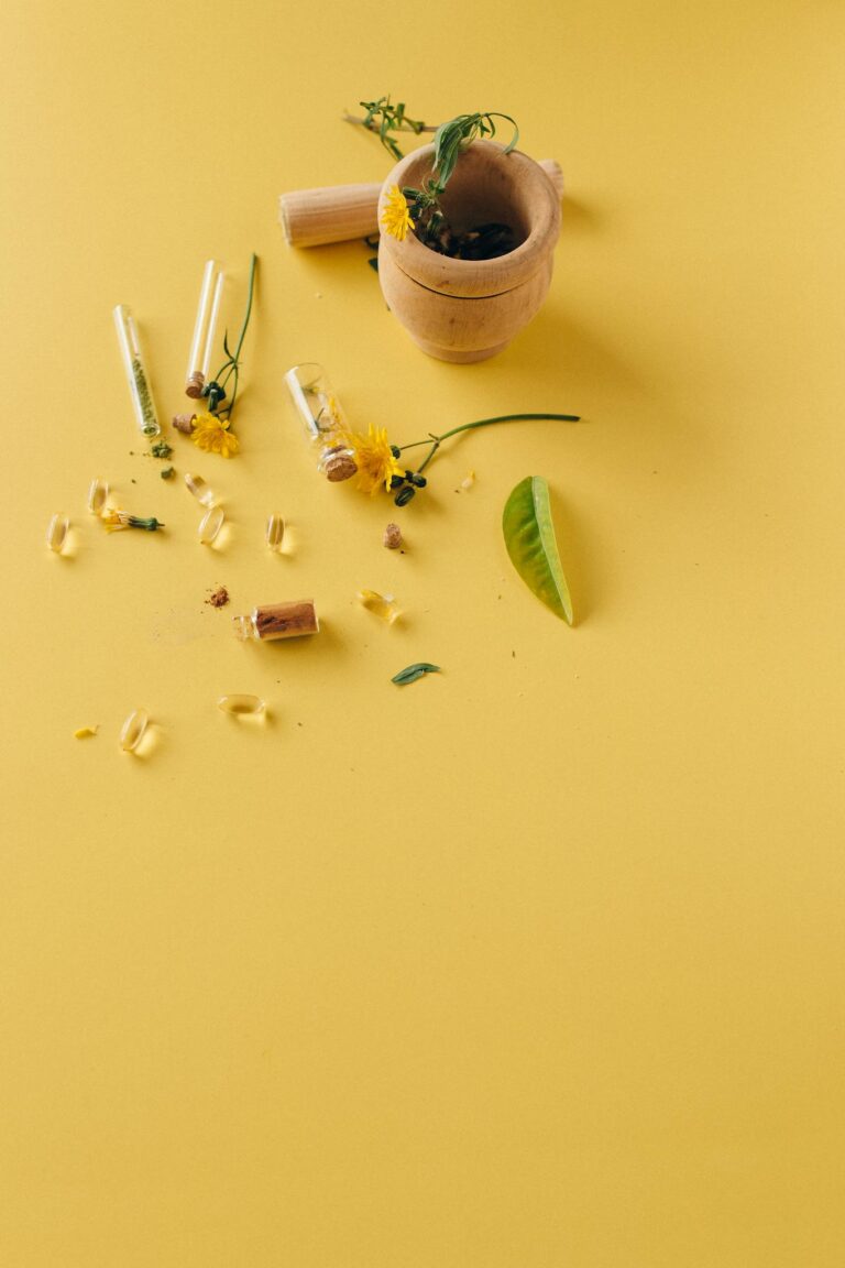 Natural herbal supplements and remedies displayed with a mortar and pestle on a vibrant yellow surface.